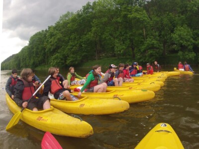 Studerende padle på en flod med kajakker, flåder og kanoer - skoletur til Tjekkiet. En dags eventyr fra Prag.