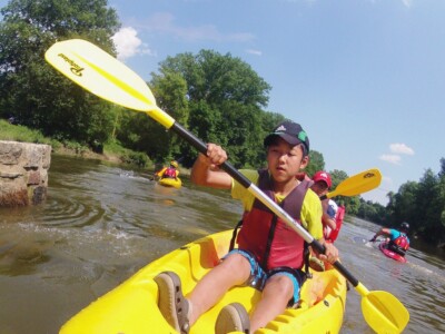 Studerende padle på en flod med kajakker, flåder og kanoer - skoletur til Tjekkiet. En dags eventyr fra Prag.